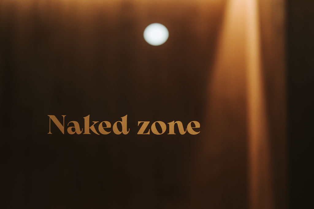 Das Bild zeigt die Aufschrift "Naked zone" an der Glaswand der Sauna im Arthotel Lasserhaus 4****s in Brixen, Südtirol