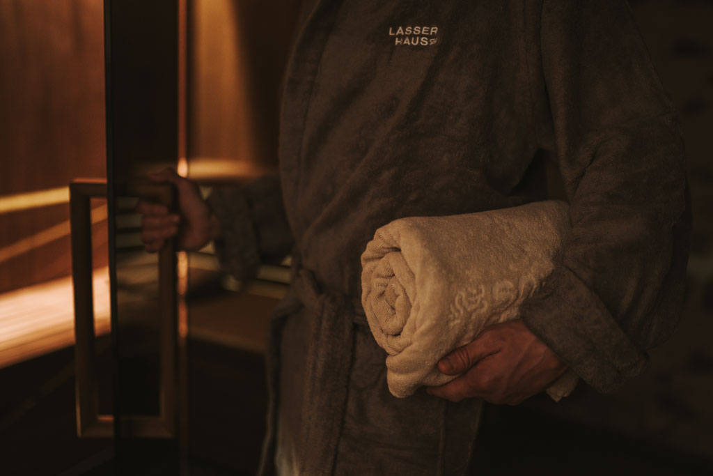 Eine Person, bekleidet mit einem Bademantel, betritt die Sauna im Arthotel Lasserhaus 4****s in Brixen, Südtirol